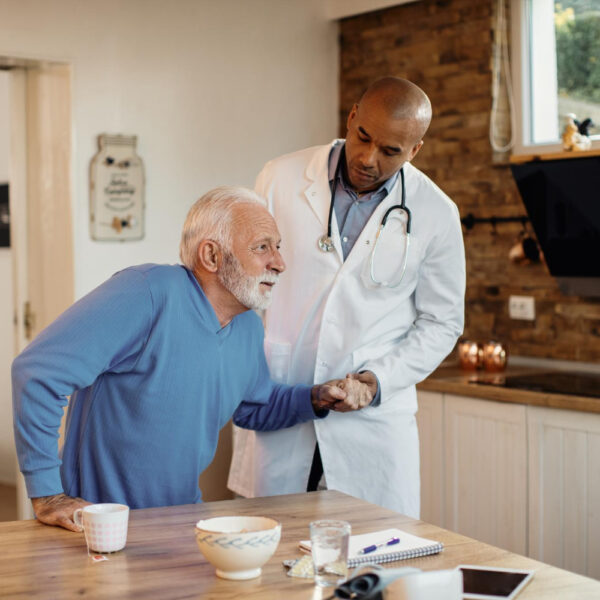 african-american-doctor-helping-senior-man-get-up-from-chair-during-home-visit african-american-doctor-helping-senior-man-get-up-from-chair-during-home-visit